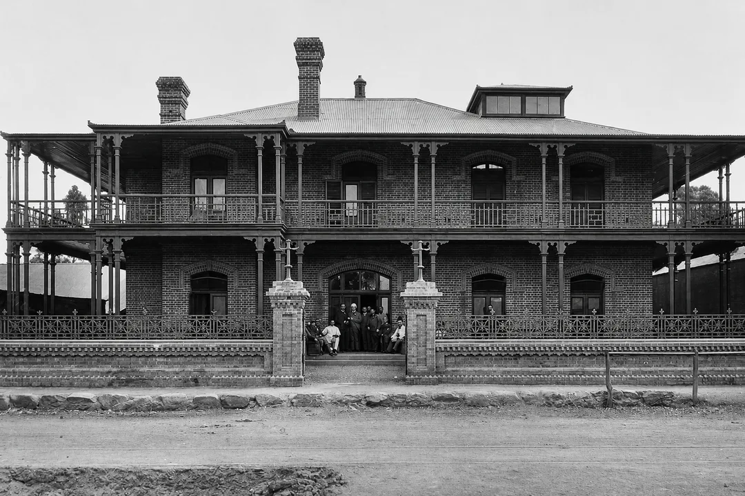 The second Kimberley Club on Du Toitspan Road, showing the two-storey verandahs, raised roof lantern, front chimney, entrance gates and horse-hitching rail.