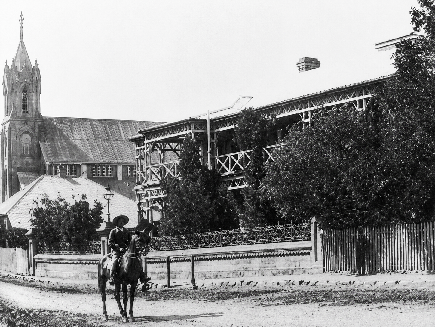 The original Kimberley Club on Du Toitspan Road, Kimberley, 1882–1886, with timber verandahs, raised roof lantern with clerestory windows and horse-hitching rail.