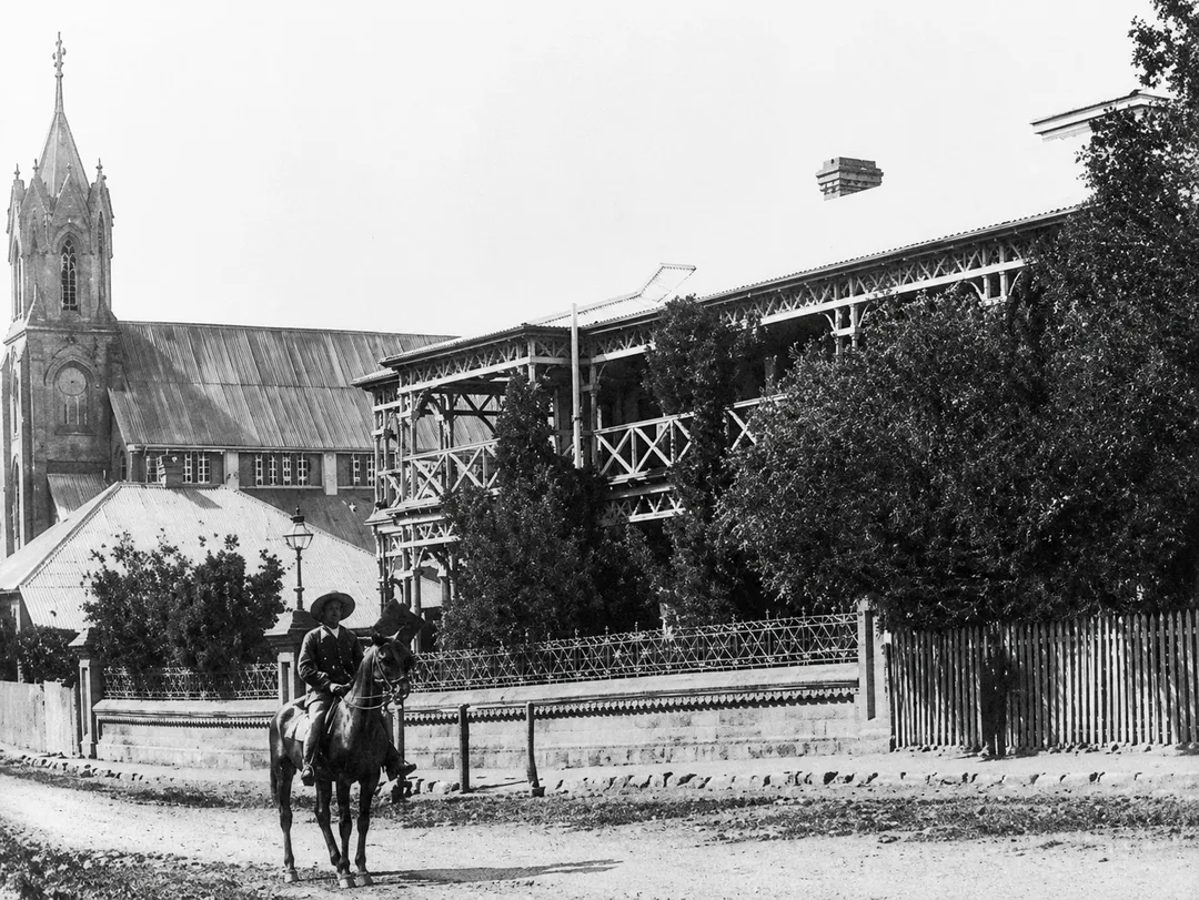 The original Kimberley Club on Du Toitspan Road, Kimberley, 1882–1886, with timber verandahs, raised roof lantern with clerestory windows and horse-hitching rail.
