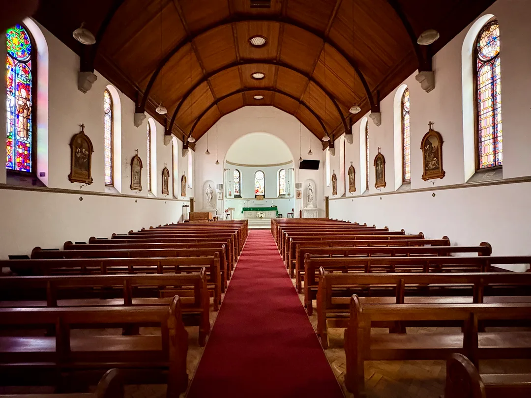 Interior of the College Chapel at St Patrick's CBC showing wooden pews, a central aisle, timber ceiling and stained-glass windows.
