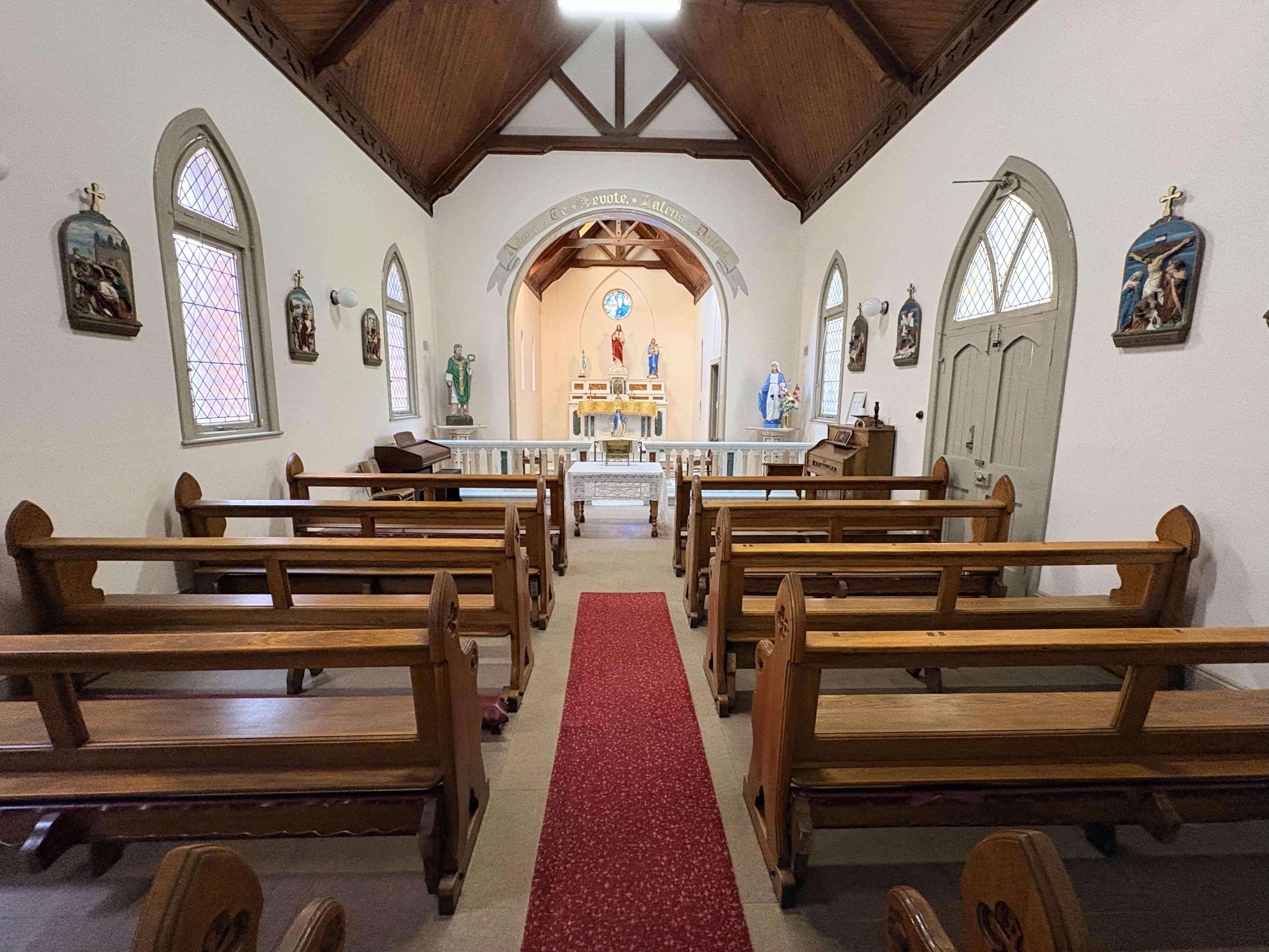 Interior of the Holy Ghost Chapel at St Patrick's CBC, showing wooden pews, a central aisle and the sanctuary viewed from the former vestibule.