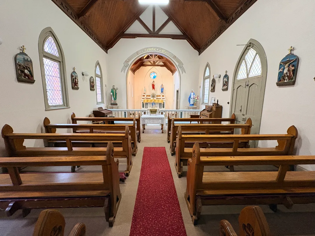 Interior of the Holy Ghost Chapel at St Patrick's CBC, showing wooden pews, a central aisle and the sanctuary viewed from the former vestibule.