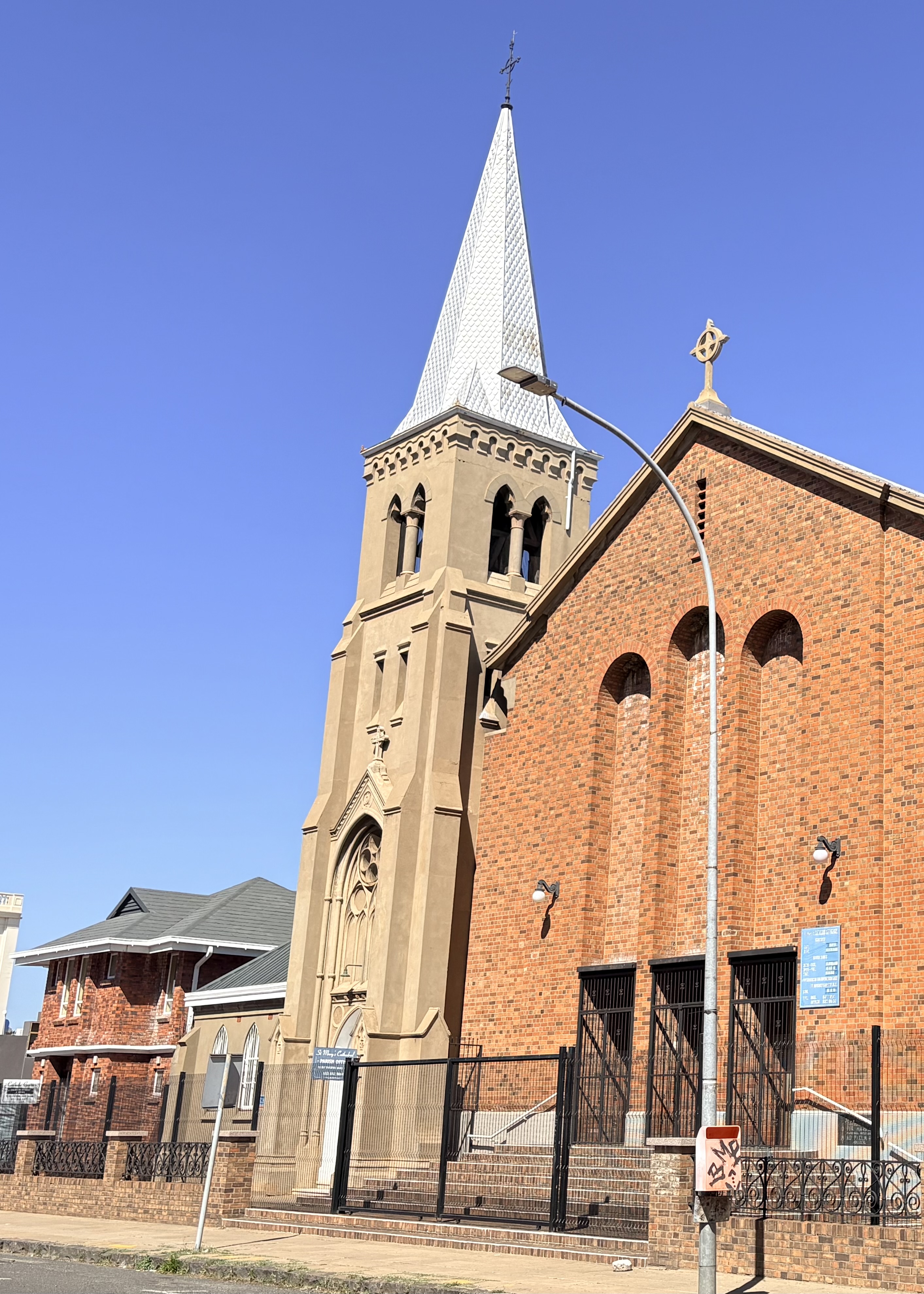 St Mary’s Cathedral in Kimberley after reconstruction, showing the surviving 1912 masonry bell tower beside the new brick cathedral building completed from 1940.