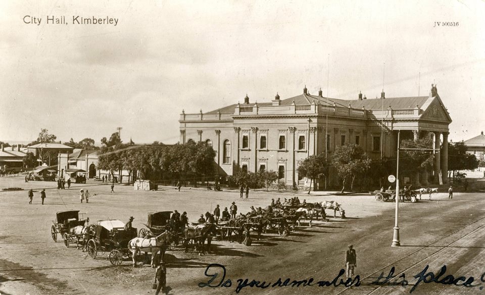 Historic view of Kimberley Town Hall with horse-drawn vehicles in the surrounding streets.